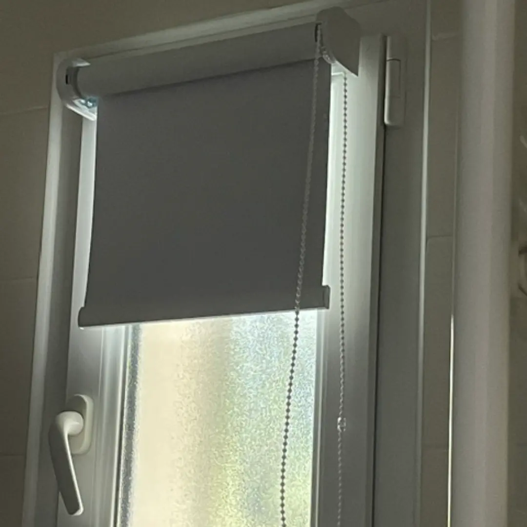 Store enrouleur occultant semi ouvert fenêtre de salle de bain